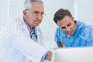 Surgeon and doctor discussing over personal computer