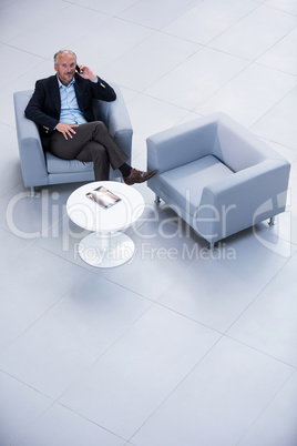 Businessman sitting on a chair and talking on mobile phone