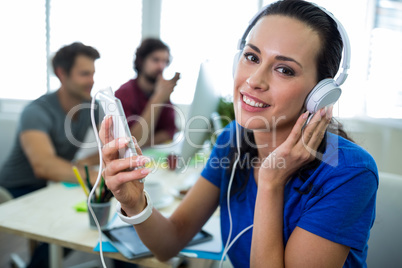 Portrait of female business executive listening to music on mobile phone