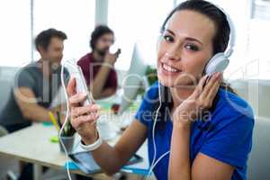 Portrait of female business executive listening to music on mobile phone