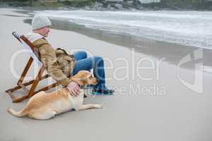 Man pampering dog while sitting on chair