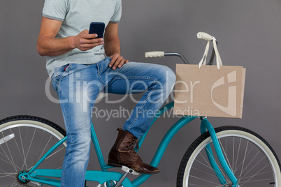 Man sitting on a bicycle and using mobile phone