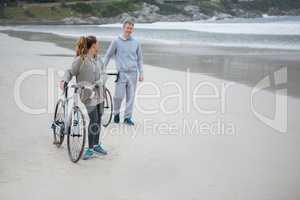 Couple with bicycle interacting with each other on beach