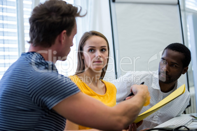 Graphic designers interacting with each other while working at desk Graphic designers interacting with each other while working at desk