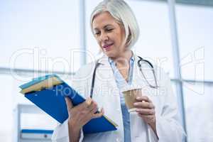 Female doctor holding medical file and coffee cup
