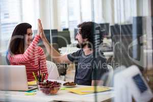 Graphic designers giving high five at their desk