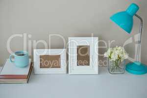 Picture frames, coffee cup with table lamp and flower vase