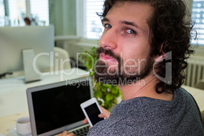 Graphic designer using mobile phone at his desk