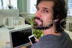 Graphic designer using mobile phone at his desk