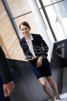 Businesswoman holding a digital tablet and climbing staircase in office building