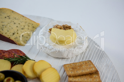 Brie cheese with crackers and ingredients on wooden board