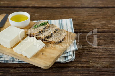 Gouda cheese, brown bread slices and lime juice with knife on chopping board