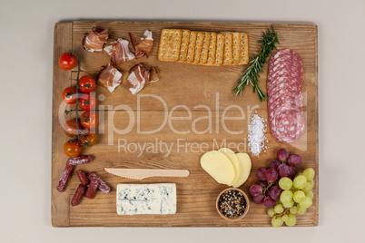 Roquefort cheese, biscuits and ham with various ingredients on chopping board