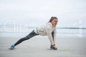Woman performing stretching exercise on beach