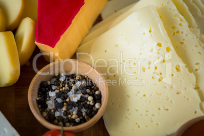 Variety of cheese with spices and sea salt on wooden board