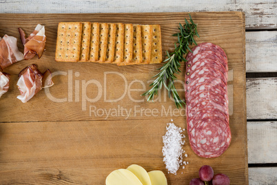 Roquefort cheese, biscuits and ham with various ingredients on chopping board