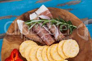 Cheese cubes, capsicum, meat, rosemary and biscuits on wooden board