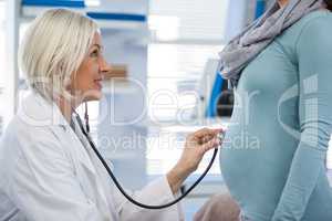 Doctor examining pregnant woman with a stethoscope