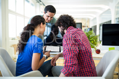 Team of graphic designers discussing over digital tablet