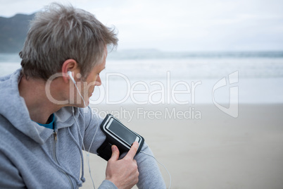 Man listening music on mobile phone at beach