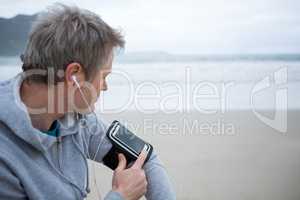 Man listening music on mobile phone at beach