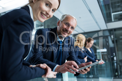 Businessman talking with colleague while holding digital tablet