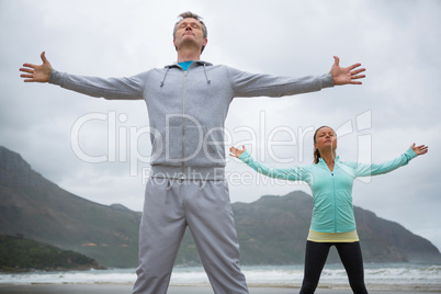 Couple standing with arms outstretched on beach Couple standing with arms outstretched on beach