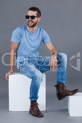 Man in blue t-shirt and sunglasses sitting on a block