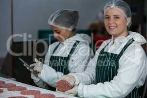 Female butchers maintaining records over digital tablet