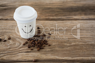 Coffee beans and disposable coffee cup with smiley face