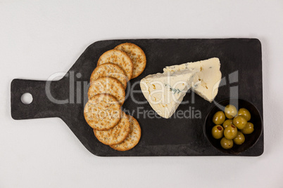 Crispy biscuits, cheese and bowl of green olives on chopping board