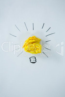 Light bulb drawn around crumbled yellow paper