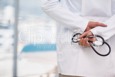 Mid-section of doctor holding stethoscope