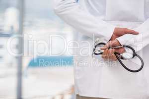 Mid-section of doctor holding stethoscope