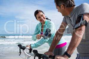 Couple leaning on bicycle while using mobile phone