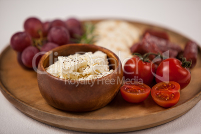 Crispy biscuits, cherry tomatoes, grapes and bowl of cheese on wooden board