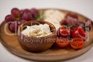 Crispy biscuits, cherry tomatoes, grapes and bowl of cheese on wooden board