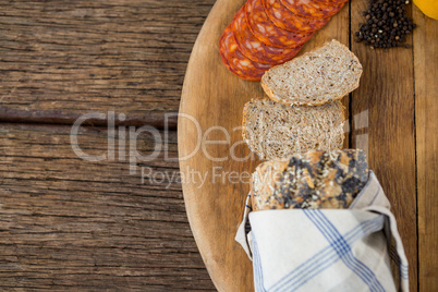 Slices of bread, meat and black pepper on wooden board