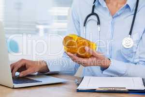 Doctor maintaining record of medicine in laptop