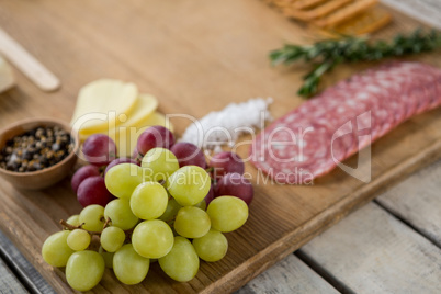 Grapes and ham with various ingredients on chopping board