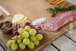 Grapes and ham with various ingredients on chopping board