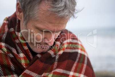 Man wrapped in shawl looking down