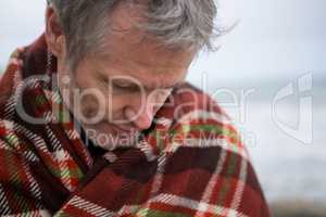 Man wrapped in shawl looking down