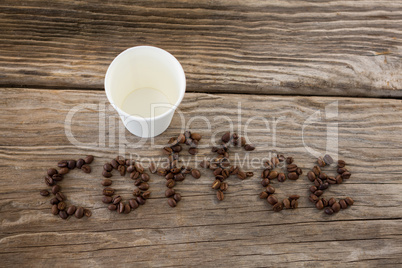 Coffee beans arranged in coffee word with disposable cups