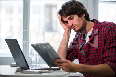 Graphic designer using laptop and digital tablet at his desk