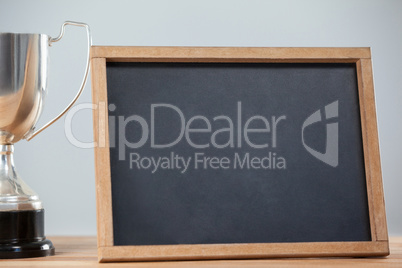 Trophy and chalkboard on wooden table