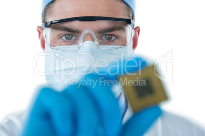 Doctor wearing protective glasses and surgical mask holding electronic chip