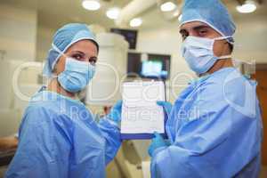 Portrait of male and female surgeons holding clipboard
