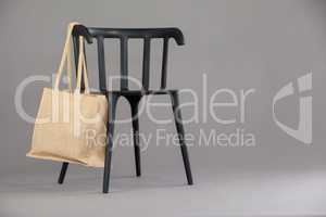 Beige colored shopping bag hanging on black chair