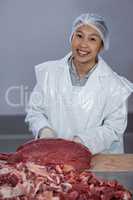 Butcher with raw meat on worktop at meat factory